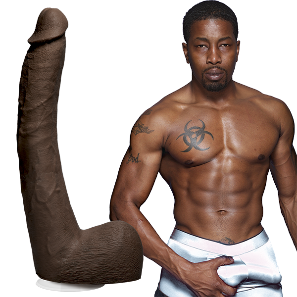 A tattooed, shirtless Isiah Maxwell poses confidently next to Doc Johnsons Signature Cocks ULTRASKYN 10 Cock. The lifelike, cylindrical, and textured dildo stands on display, creating a striking juxtaposition.