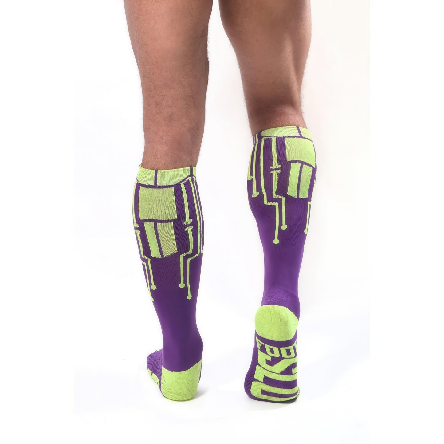 A person, back to the camera, wears *ssTricks CyberTech Socks Neon Yellow & Purple—purple knee-highs with neon yellow circuit designs and glowing heels/toes. FOOT is visible on one sock sole.