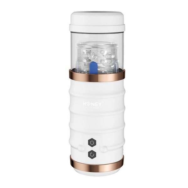 The Warrior Auto Thrusting Male Masturbator by Honey Play Box is a portable white pleasure product with a transparent top and elegant rose gold accents, designed for convenience and featuring intuitive controls for on-the-go use.