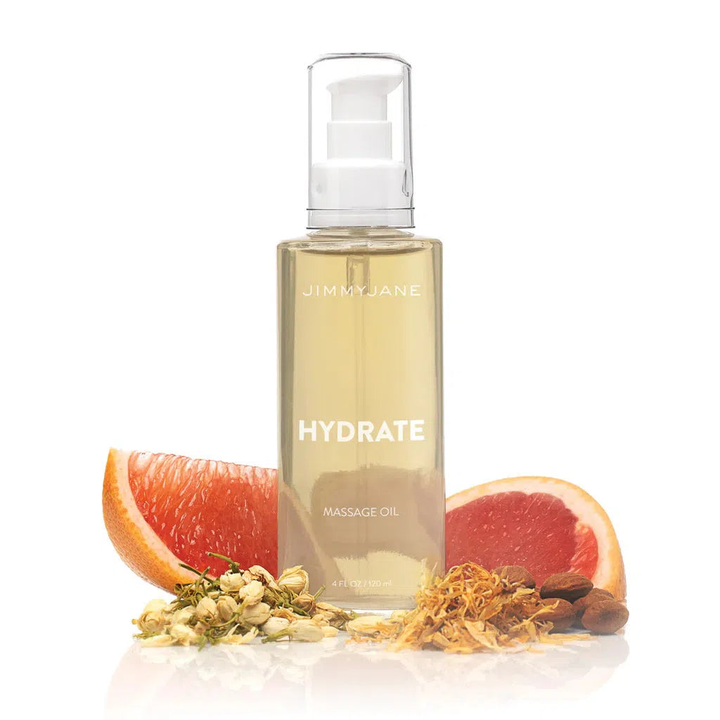 A 4 oz clear bottle of Pipedream products JimmyJane Hydrate Massage Oil with a pump is shown in front of grapefruit slices, dried flowers, and almonds on a white background.