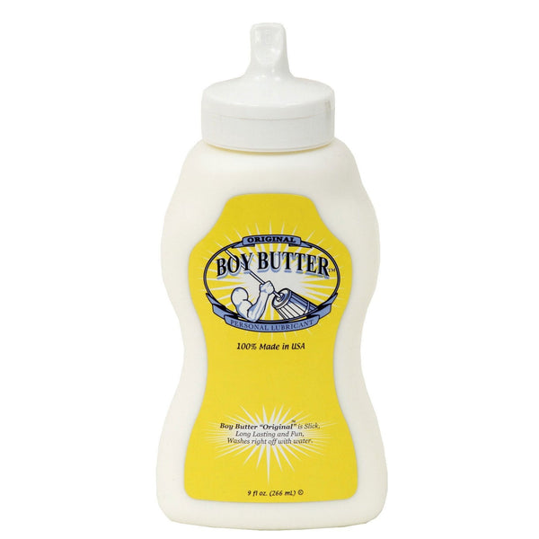 The Boy Butter Churn Style Squeeze Bottle (9 oz) is a white bottle featuring a muscular figure on a yellow label. It highlights 100% Made in USA, is water-soluble, washes off easily with water, and is infused with coconut oil.