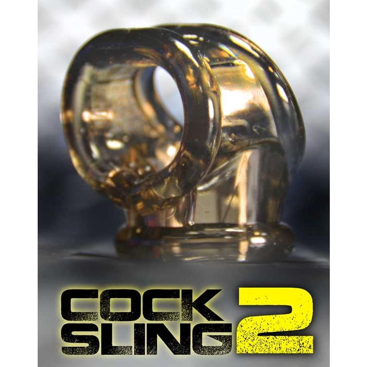 The Oxballs Cocksling 2, a transparent dual ring with a contoured design, stands out against a blurred background. Bold text promotes Cock Sling 2, emphasizing its appeal as both a cock ring and ball stretcher from the Oxballs brand for enhanced pleasure.
