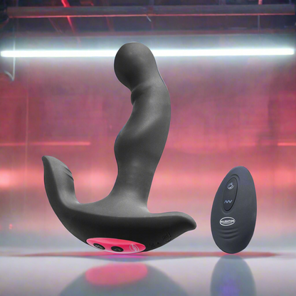 The Malesation Rimming Hero, a black and pink prostate massager with curved design and control buttons, floats next to a sleek black remote. Both are crafted from body-safe silicone and set against a neon-lit pink and purple background. Brand: Malesation.