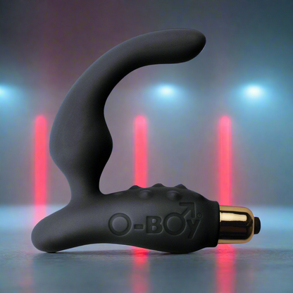 The Rocks Off O Boy 7, a sleek black prostate massager with a curved design for hands-free pleasure, features O-BOY embossed on its body. It has a metallic gold base and is ideal as a beginner prostate tool, set against blue and red vertical lights.