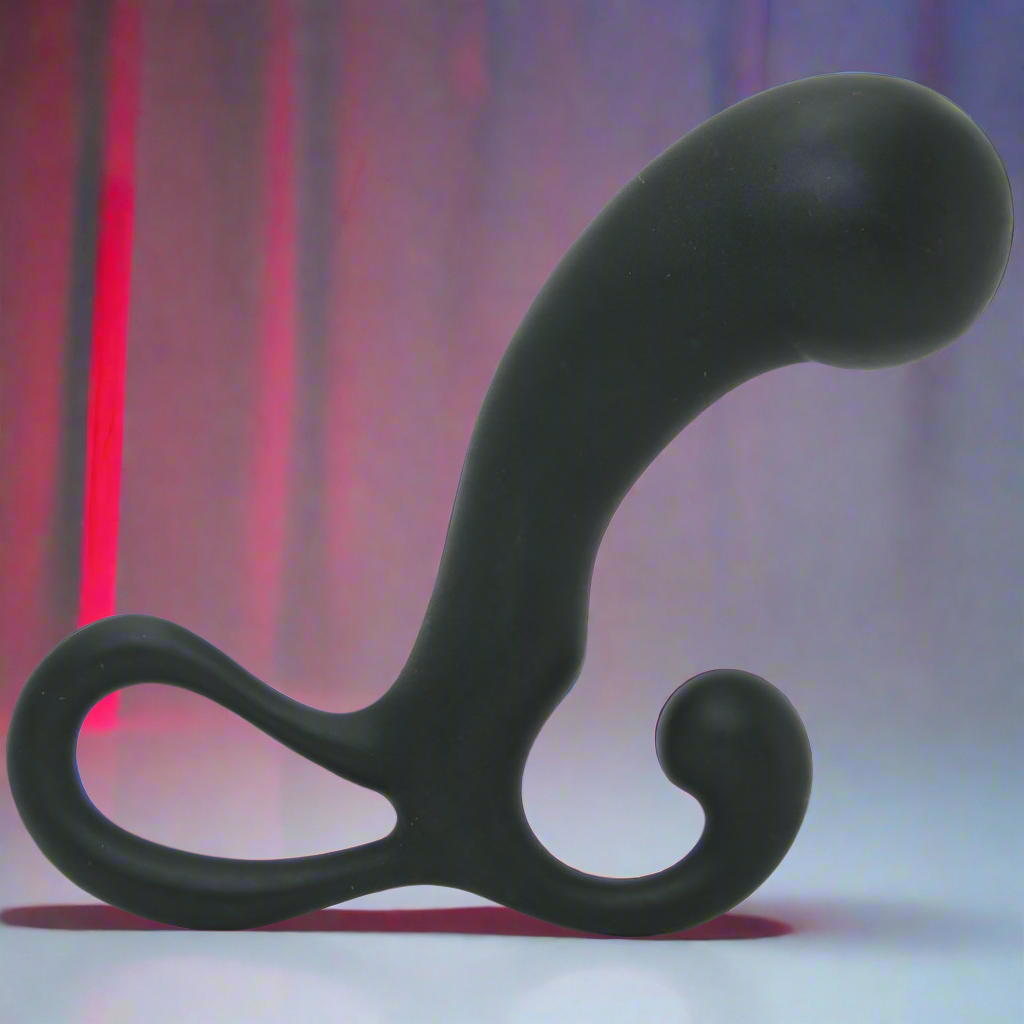 The OptiMale P Massager by Optimale is a sleek black, curved prostate massager with a looped handle and bulbous end. It stands out against blurred red and gray tones, delivering sophisticated P-spot pleasure with elegant contrast.