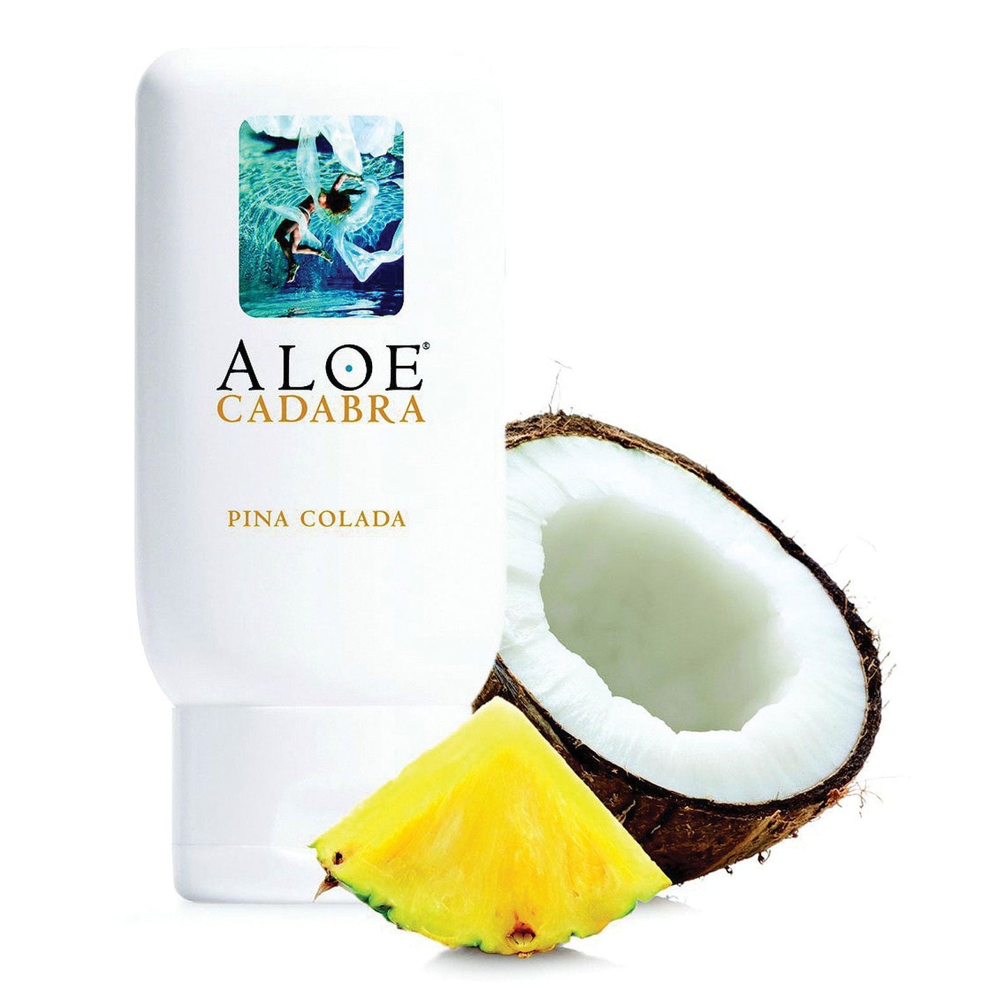 An Aloe Cadabra Organic Lubricant bottle sits next to a halved coconut and pineapple wedge. Enhanced with aloe vera, its glycerin-free formula is reflected in vibrant tropical imagery on the label.