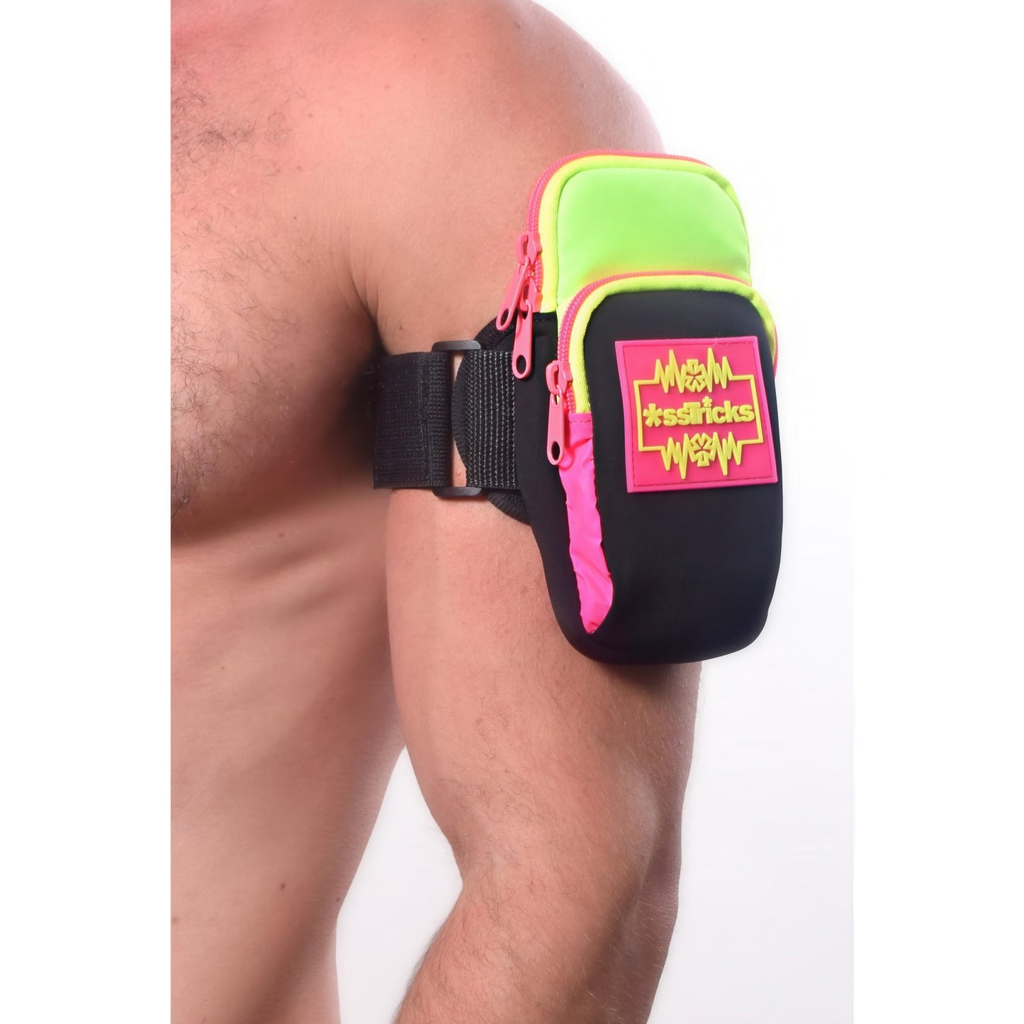 A person wears the *ssTricks Ekg Arm Bag in Neon green and pink with a black strap on their upper arm. Made from water-resistant neoprene, it features #essentials text and reflective side paneling for visibility.