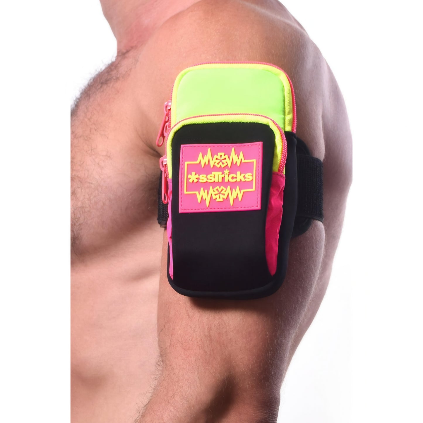 A muscular person wears the Ekg Arm Bag in Neon by *ssTricks, made from water-resistant neoprene with a green, pink, and black zigzag design, reflective side panels, and shown against a plain white background.