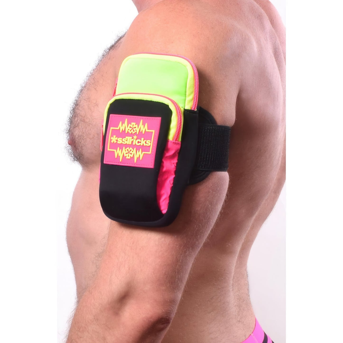 A person wears an Ekg Arm Bag in Neon by *ssTricks in pink, green, and black with the logo on the front. The water-resistant neoprene pouch has reflective side panels and a strap that secures it to the upper arm.