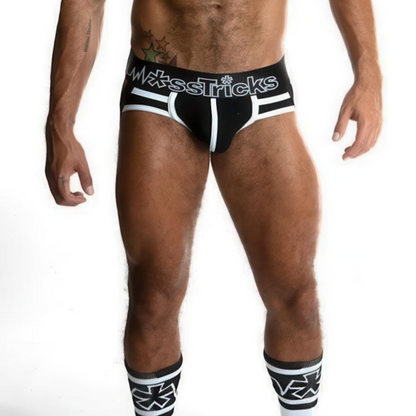 A muscular male model wears *ssTricks Juku Jock - Monochrome black and white briefs and matching geometric knee-high socks, striking a pose against a white background. His face is not shown.