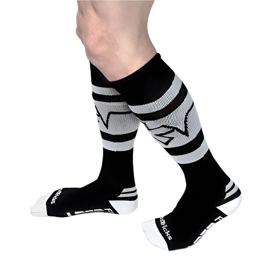 A person models *ssTricks Knee High Socks with Hidden Pockets in Black & White, featuring geometric patterns and text near the toes, against a white background.