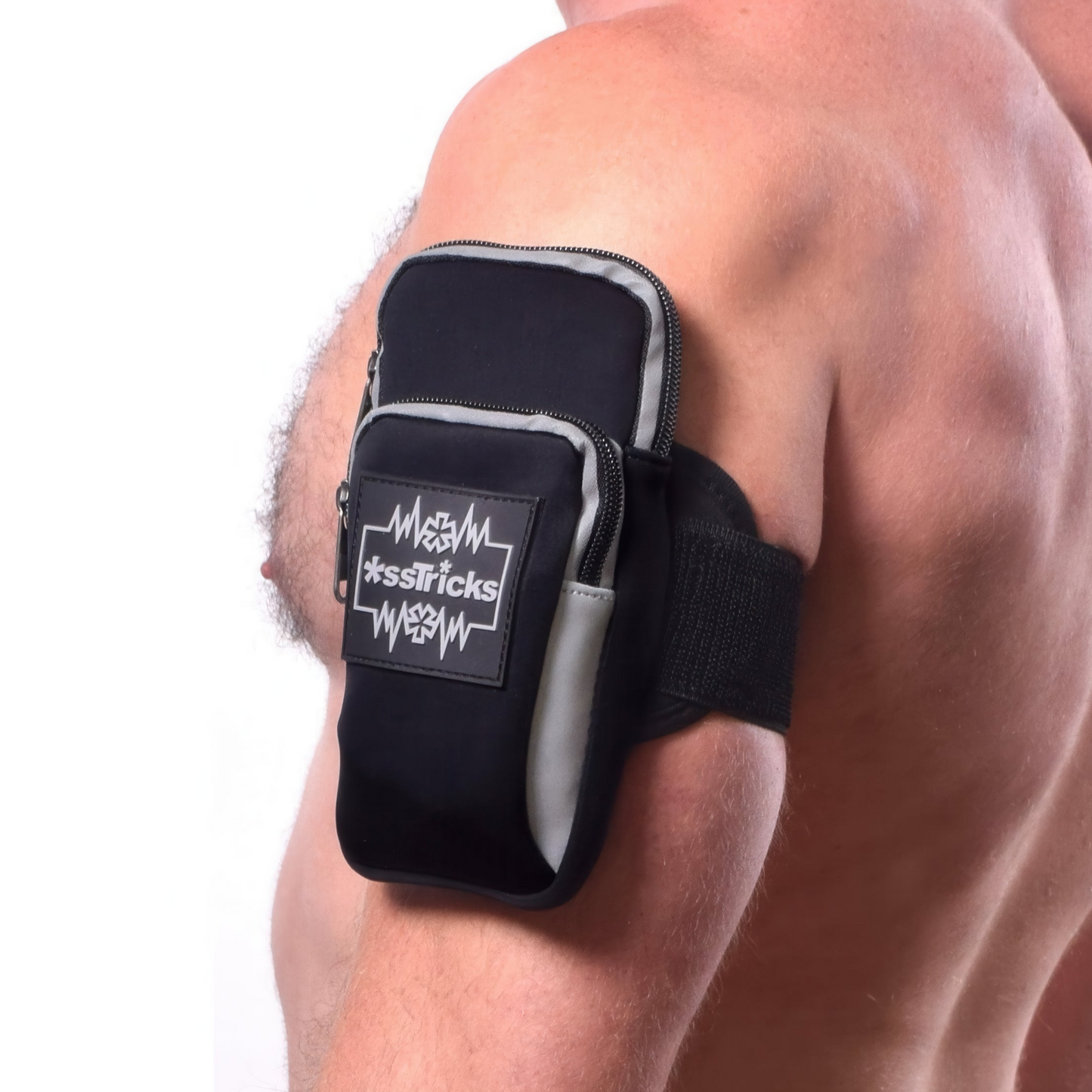 A close-up of a person’s upper arm wearing the EKG Arm Bag in Black by *ssTricks, an adjustable, water-resistant neoprene pouch with a zipper and brand logo, shown against a white background.