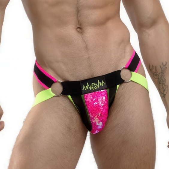 Sporting the SEQUIN JOCKSTRAP | Notorious Neon by *ssTricks, featuring pink sequins, black straps with metal rings, and neon accents, a person embraces a daring look. Their bear and trees tattoo on the left arm contrasts strikingly against a plain white background, embodying bold fetishwear.