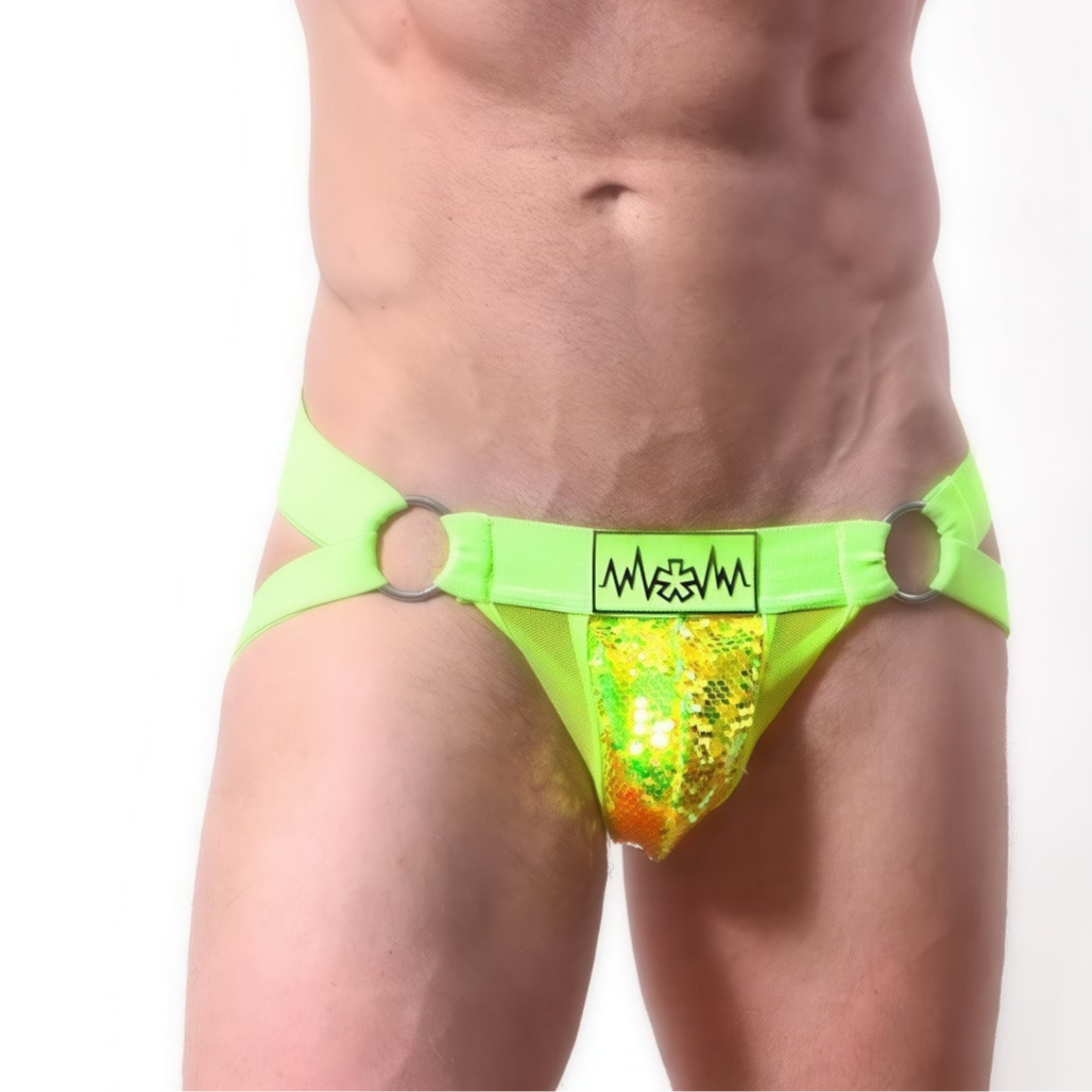 A person models the *ssTricks SEQUIN JOCKSTRAP in neon green, showcasing metallic accents and two metal rings on each side for an adjustable fit, all against a plain white background.