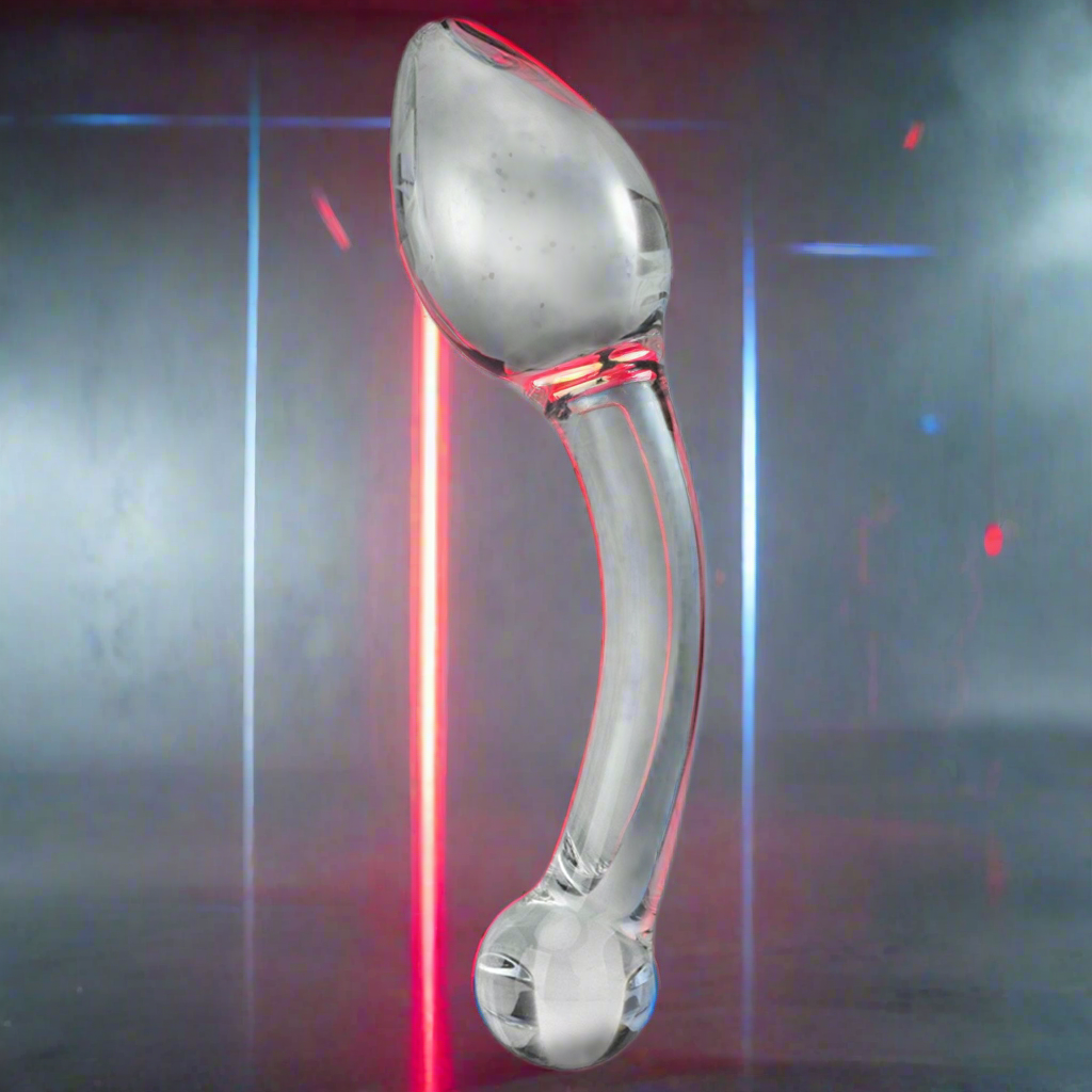 The Gläs Pure Indulgence Anal Prostate Toy by Gläs, a transparent hand-blown glass object, stands upright on a reflective surface with red and blue neon lights in the background, creating a futuristic vibe ideal for P-spot stimulation.