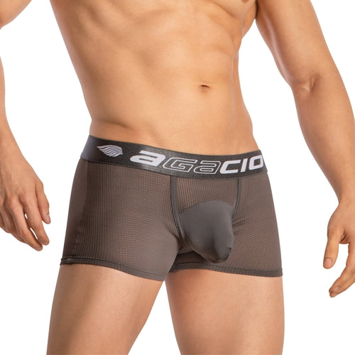 A person wears Agacio Boxer Mesh Trunks with a brown sheer mesh design and a supportive pouch. The black waistband displays Agacio in white. They stand against a plain white background, hands by their sides.