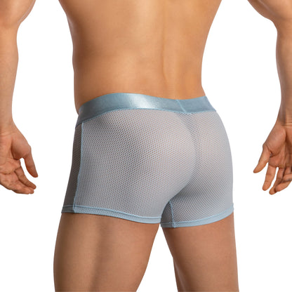 Viewed from the back, a person wears Agacio Boxer Mesh Trunks with Pouch in light blue. Their hands are at their sides, and the shiny waistband contrasts with the supportive pouch and textured sheer mesh. The backdrop is minimalist white.