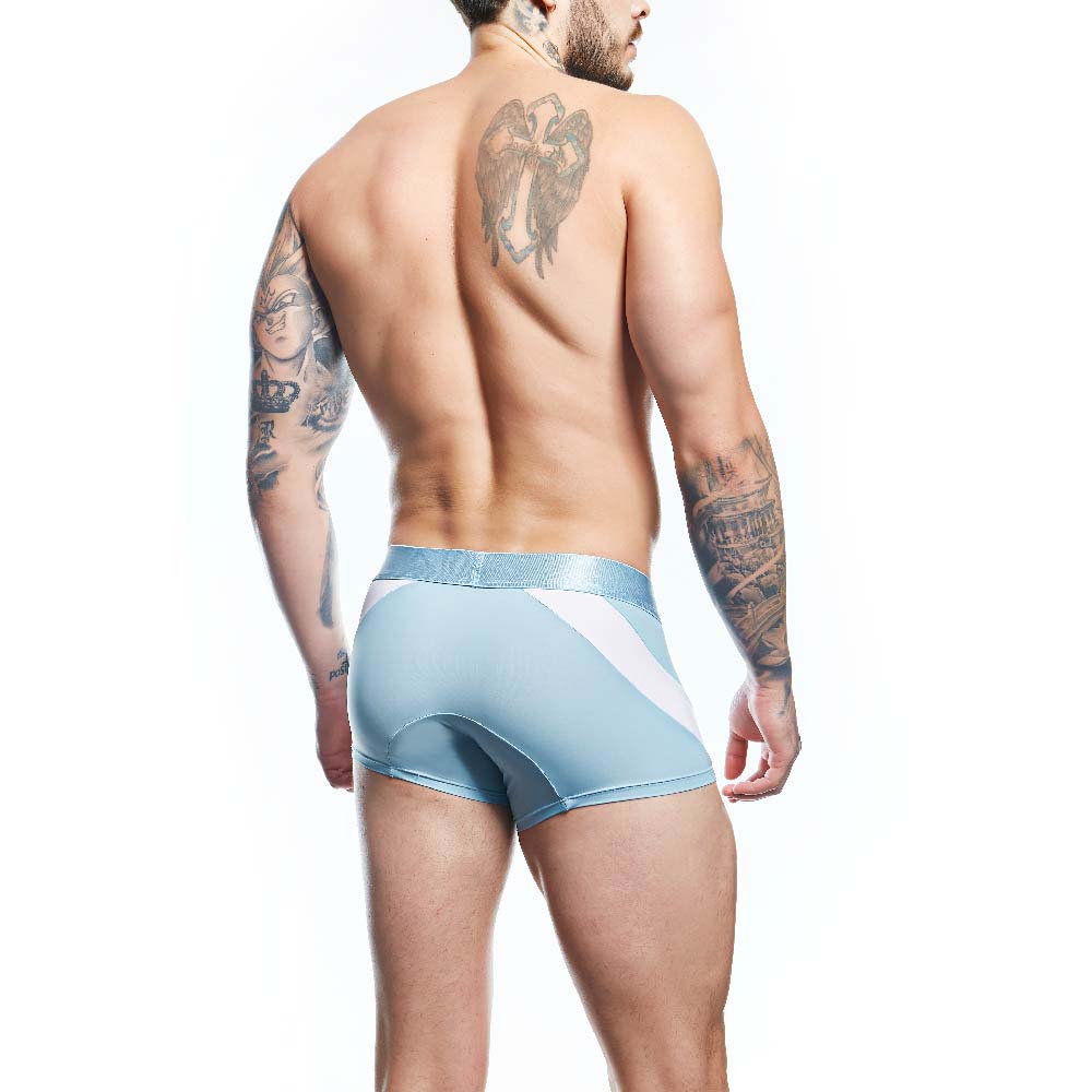 A tattooed man stands confidently in Agacio Boxer Trunks Comfortable Underwear, made from a premium fabric blend. Facing away, his silhouette is accentuated by the contour pouch magic against a plain white backdrop.