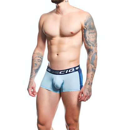A tattooed man models light blue Agacio Boxer Trunks Comfortable Underwear, featuring a dark waistband, known for comfort and support, against a plain white background.
