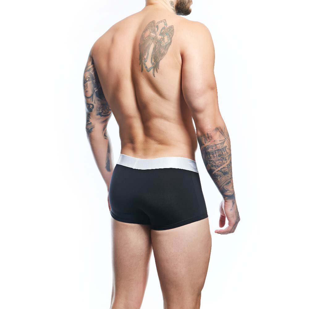 A tattooed man is standing sideways, displaying his well-defined back muscles. He wears Agacios Comfortable Underwear Boxer Trunks in black, with a supportive white waistband, set against a plain white background.