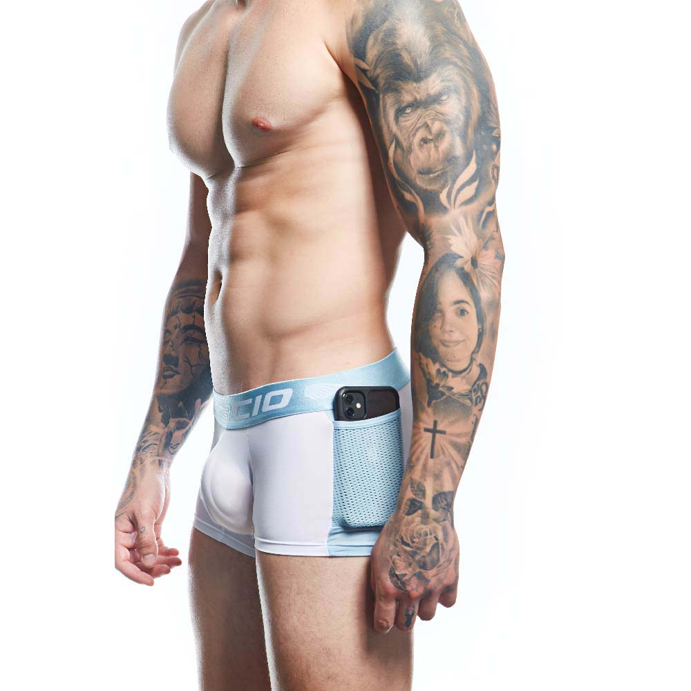 A tattooed man in profile wears Agacio Boxer Trunks Comfortable Underwear, highlighting their comfort and support. The white and blue fitted shorts with a side pocket hold a smartphone.