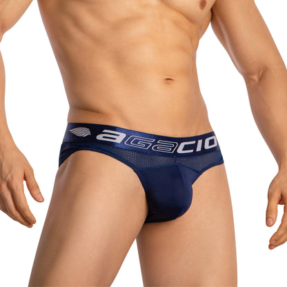 A person is wearing the Agacio Mens Sheer Brief in dark blue, showcasing a contour pouch and a waistband with Agacio printed on it. The luxurious fabric contrasts beautifully against a plain white background.