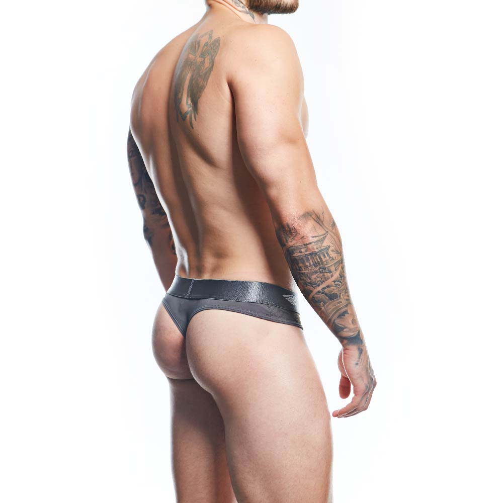 Against a plain white background, a tattooed person confidently wears Agacio Thong for Men in black leather. They embody the sleek, minimalist aesthetic of the Agacio brand, crafted from premium fabric blends.