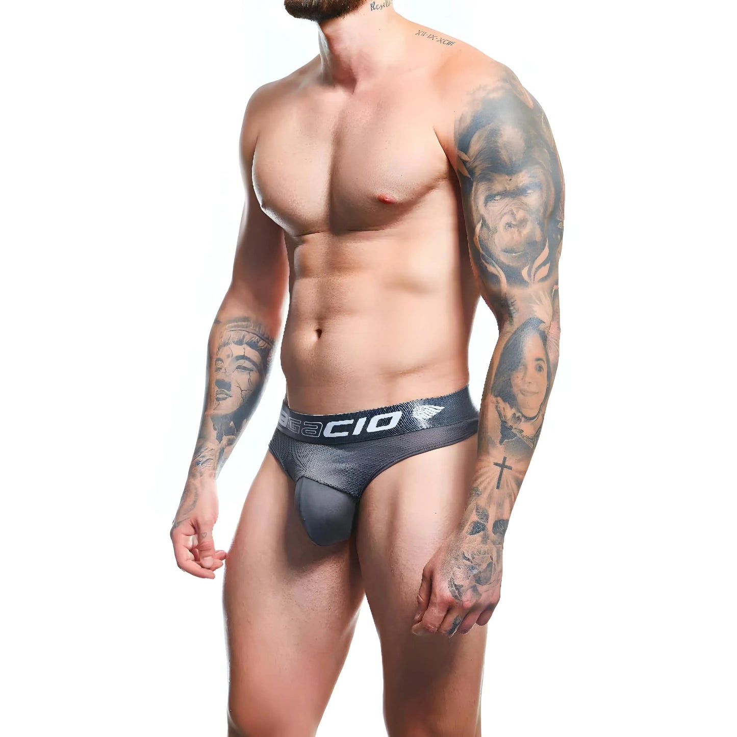 A tattooed man wears Agacio Thong for Men, featuring a minimalist design against a white background. Crafted from a premium fabric blend, Agacio guarantees comfort and style for the modern man.