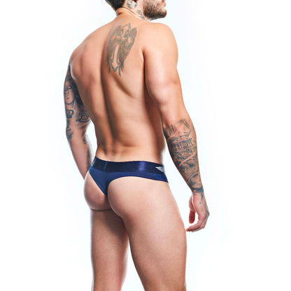 A tattooed man is seen from the back wearing Agacios navy blue Thong for Men, crafted from a premium fabric blend. He stands against a plain white background, highlighting the minimalist design and detailed tattoos on his arms and back.