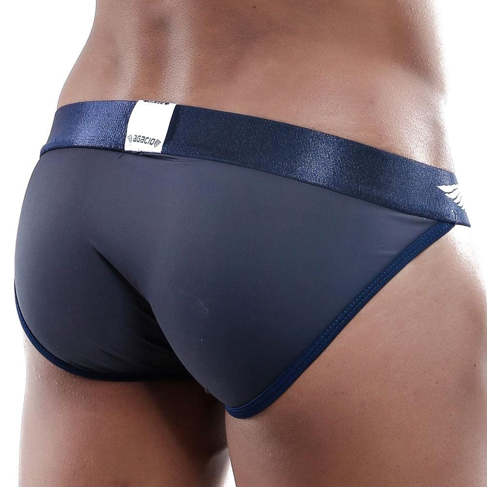 A close-up of an individual wearing Agacio Bikini swim briefs features a shiny waistband, emphasizing the C-shape pouch and premium fabric blend against a plain backdrop to highlight the sleek design.