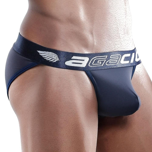 A muscular person wears navy Agacio Bikini underwear with a wide waistband adorned with the agacio logo and wing design. The C-shape pouch and premium fabric blend deliver both comfort and style.
