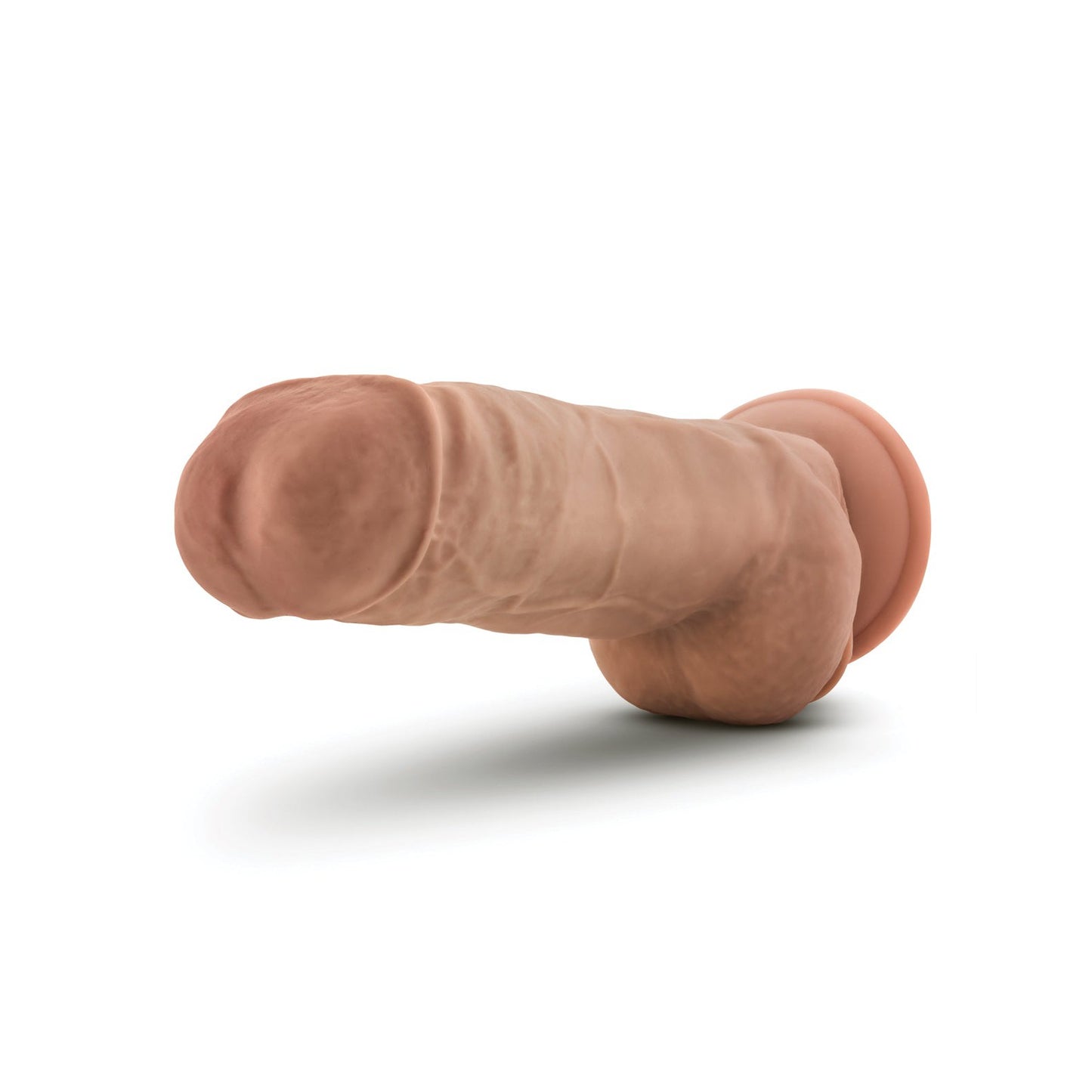 The Blush Au Naturel 10 Big Boy Realistic Dildo by Blush Novelties, featuring FlexiShaft Technology for enhanced movement, is displayed from the side. It showcases anatomical details, a sturdy suction cup base, lifelike texture, and dual density color against a plain white background.