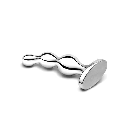 A metallic, polished Stainless Steel Anal Beads from b-vibe rests on a flat surface. Its wavy, bulbous design features an oval handle engraved with a logo on a white background, blending art and function for prostate stimulation.