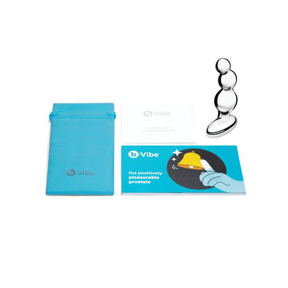 The b-Vibe Stainless Steel Anal Beads, a silver device with three bulb shapes made of stainless steel, is shown on a clean white background. Accompanied by a blue pouch, an informational booklet, and instruction manual, its perfect for beaded anal or prostate stimulation.