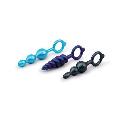 The b-Vibe Butties Beaded Bundle features three silicone anal plugs in blue, purple, and black. Ideal for training, each plug has spherical and spiral designs with a ring handle for easy use, elegantly displayed on a white background.