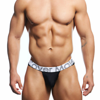 A person showcases a toned physique in a sleek black-and-white Cover Male Bikini for Men against a plain white backdrop.