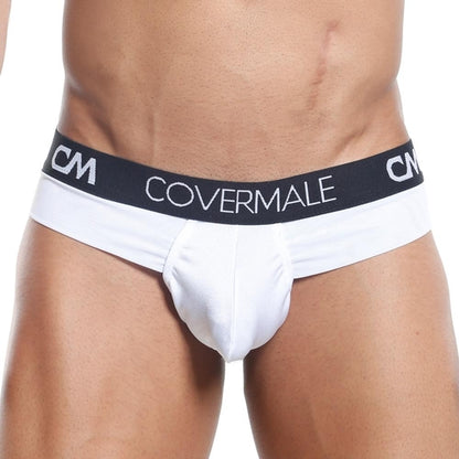 A person poses against a plain background wearing a stylish Cover Male Slip Thong, featuring cheeky coverage, a black waistband with Covermale in white letters, and bold CM lettering.