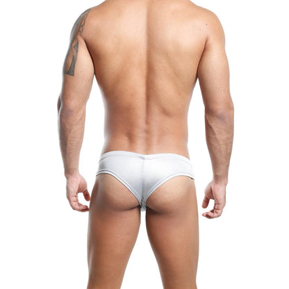 A man with a tattoo on his arm faces away, wearing Cover Male Slip Thong in light gray. The supportive hold contrasts on the white backdrop, showcasing a sheer and solid fusion that enhances both posture and style.