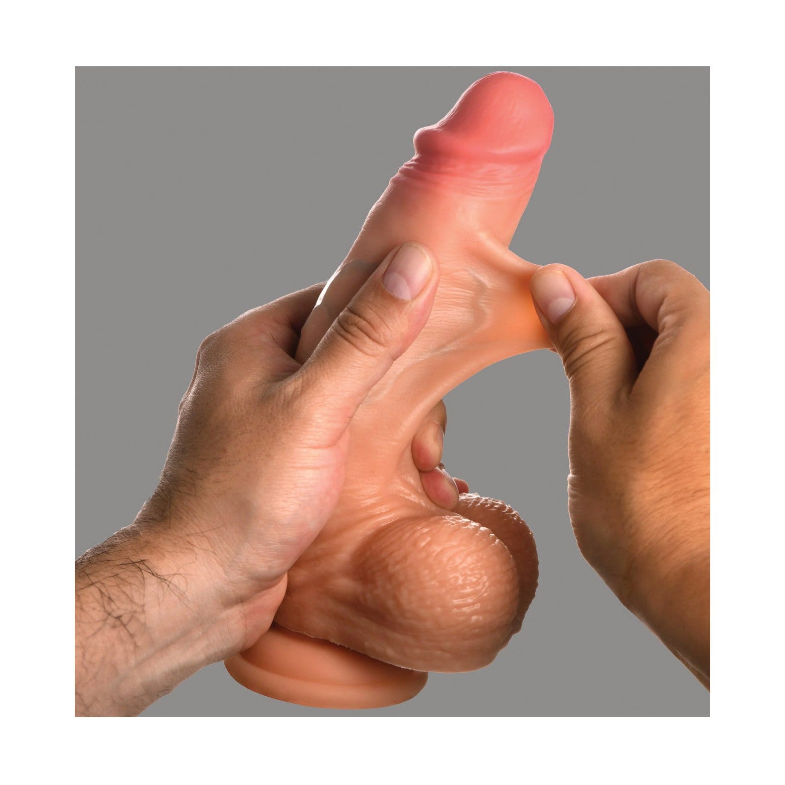 Someone holding the Curve Toys Jock Real Skin Silicone 8 Dildo With Balls by Curve Novelties, showing its flexible texture with both hands against a plain backdrop.