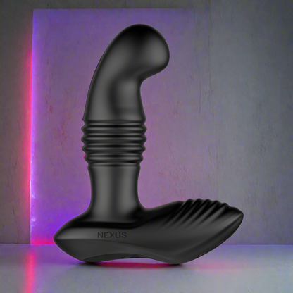 The Nexus Thrust Prostate Edition by Nexus is a black prostate massager with a ridged design, spotlighted against a textured gray background. A pink and purple hue glows from the top left corner, highlighting its sleek matte finish. This remote control device offers multiple vibrating modes.