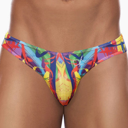A person is wearing the vibrant Daniel Alexander Explosion Slip bikini, featuring a mix of blue, red, yellow, and green. This swimwear highlights modern prints and a contouring pouch design.