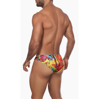 Someone is confidently wearing the Daniel Alexander Explosion Slip bikini with colorful, modern prints. The image showcases their muscular build and contouring pouch design against a plain white background, capturing them from behind.