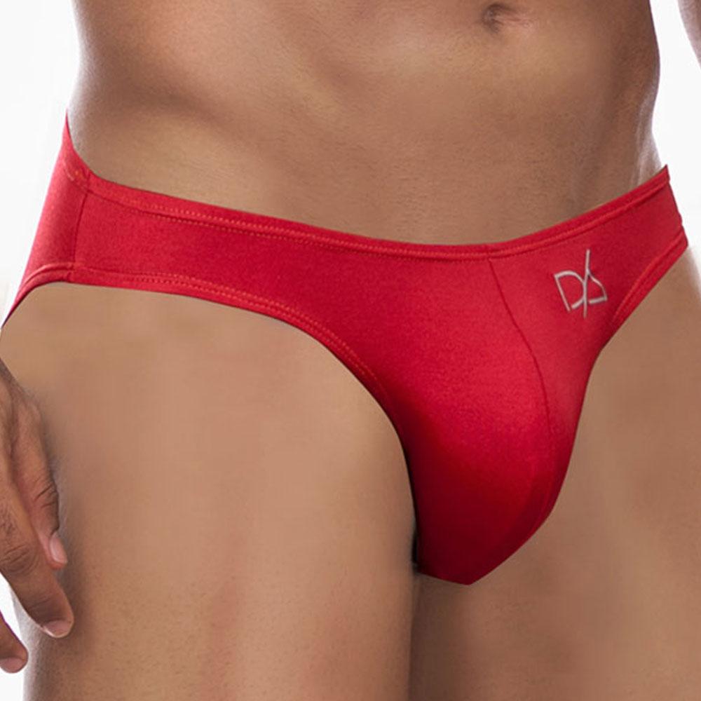 A person wears Daniel Alexander Colorful Slip Bikini briefs in vibrant red, featuring a logo on the front. The image focuses on the midsection, highlighting the fit and design with a sexy contoured pouch against a plain, neutral background.