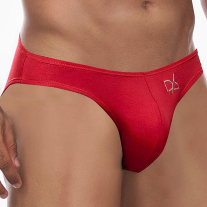 A person wears Daniel Alexander Colorful Slip Bikini briefs in vibrant red, featuring a logo on the front. The image focuses on the midsection, highlighting the fit and design with a sexy contoured pouch against a plain, neutral background.