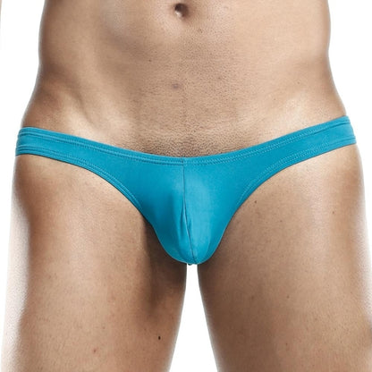 A waist-down view showcases the snug fit and striking teal color of the Daddy Slip Bikini by Daddy, with a plain background highlighting mens bikini underwear.