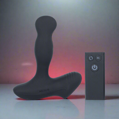 The Nexus Revo Slim Rotating Prostate Massager, a black luxury male sex toy with a curved design, stands upright beside a small black remote. Made from premium silicone, it sits against a softly lit background with a reddish glow, casting subtle reflections on the surface.