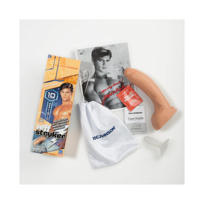 The image features the Jeff Stryker 10 Realistic Cock by Doc Johnson, made from FIRMSKYN material with textured veins for realism. Also shown are its packaging, care guide, promo photo, lube packet, suction base, and drawstring storage bag.