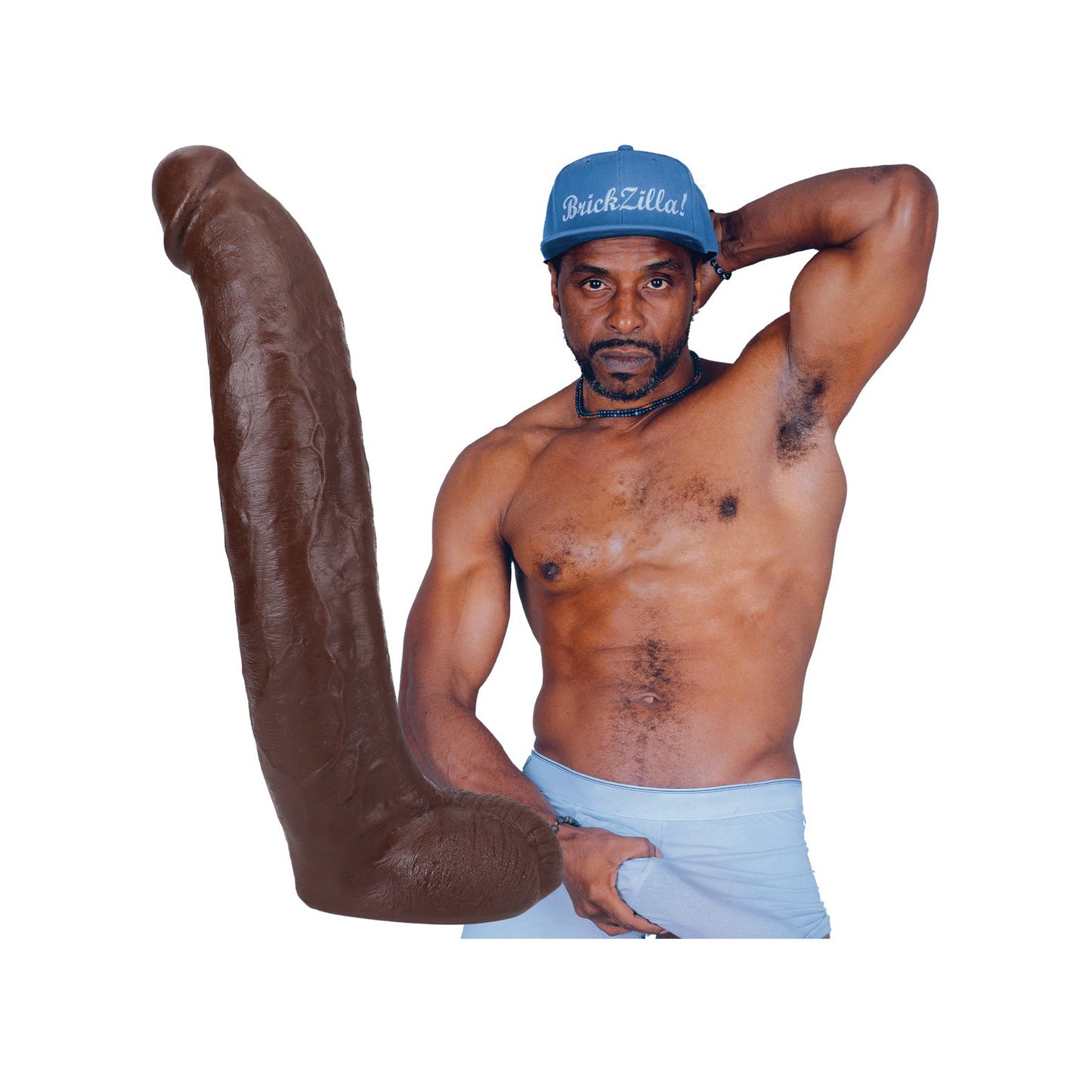 A shirtless man in a blue cap confidently poses, one arm behind his head and the other on his waistband, next to Doc Johnsons Signature Cocks ULTRASKYN 13 Cock - Brickzilla. The plain white background enhances the bold dual-density design of the large brown sculpture beside him.
