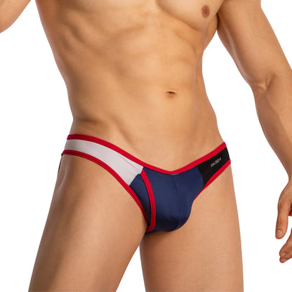 The image displays a person wearing the Daddy Provocative Rear Exposing Jockstrap, featuring bold blue, white, and red tones. A black Daddy brand label accents the waistband. Set against a plain white background, it emphasizes bold style and premium fabric quality.