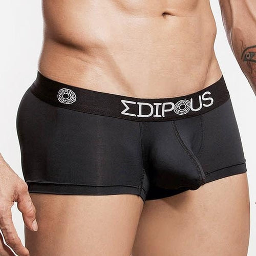 A person is wearing Edipous Eros Short Boxers, featuring a branded waistband with Greek letters. The focus is on the fit and design for comfort support, and a tattoo on their right arm is partially visible.